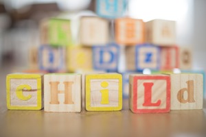 Holzspielwürfel, die das Wort Child ergeben. Foto von Pixabay/Skitterphoto.